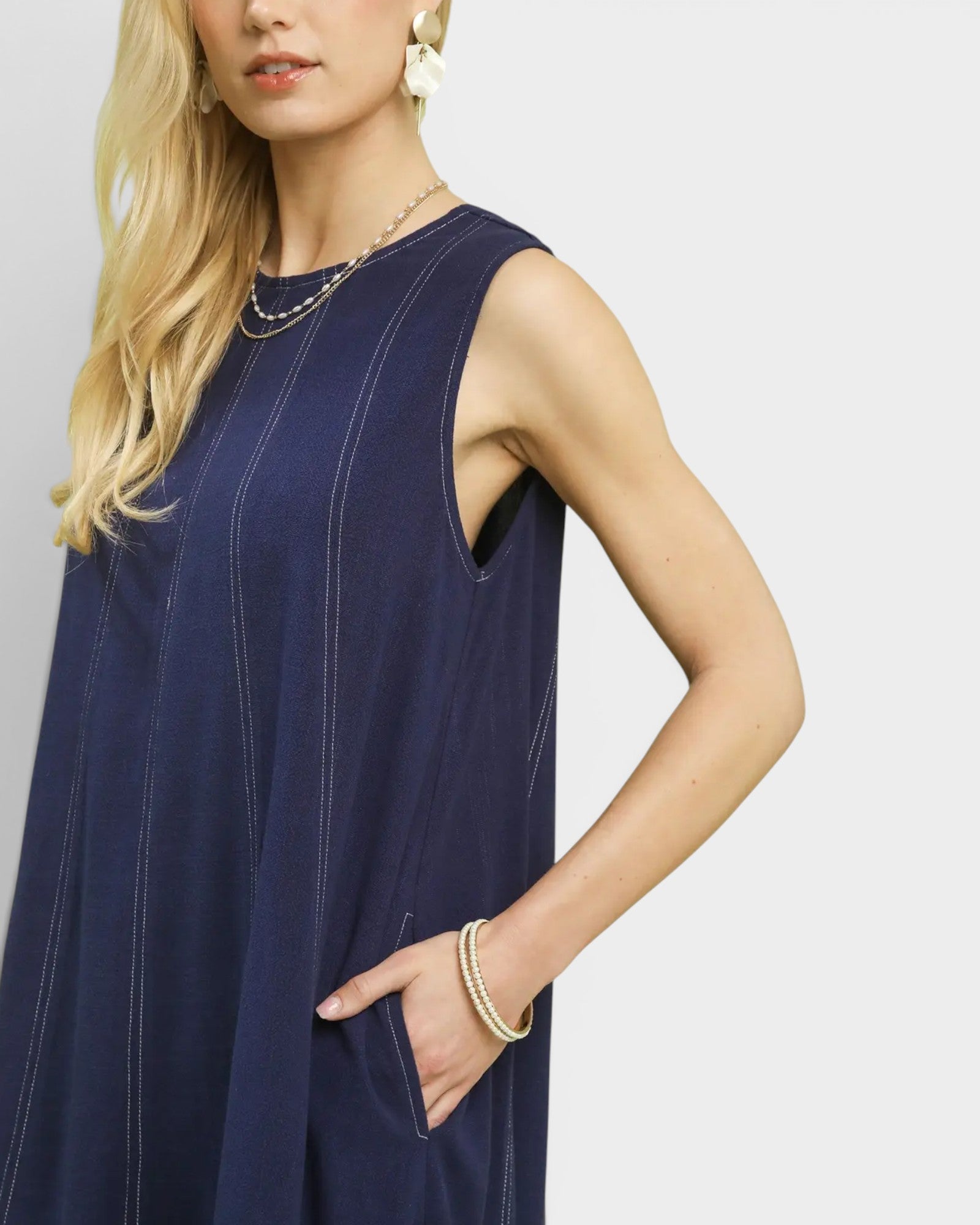 Woman wearing a navy blue sleeveless dress against a white background
