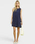 Woman wearing a navy blue dress holding a white handbag on a light gray background