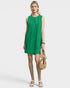 Woman wearing a green dress holding a beige handbag on a white background