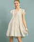 Woman wearing a beige dress with intricate details on a solid background