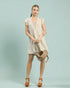 Woman wearing a beige dress holding a woven bag against a light blue background
