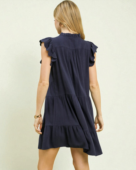 Navy blue dress with ruffled sleeves and bottom on a plain background