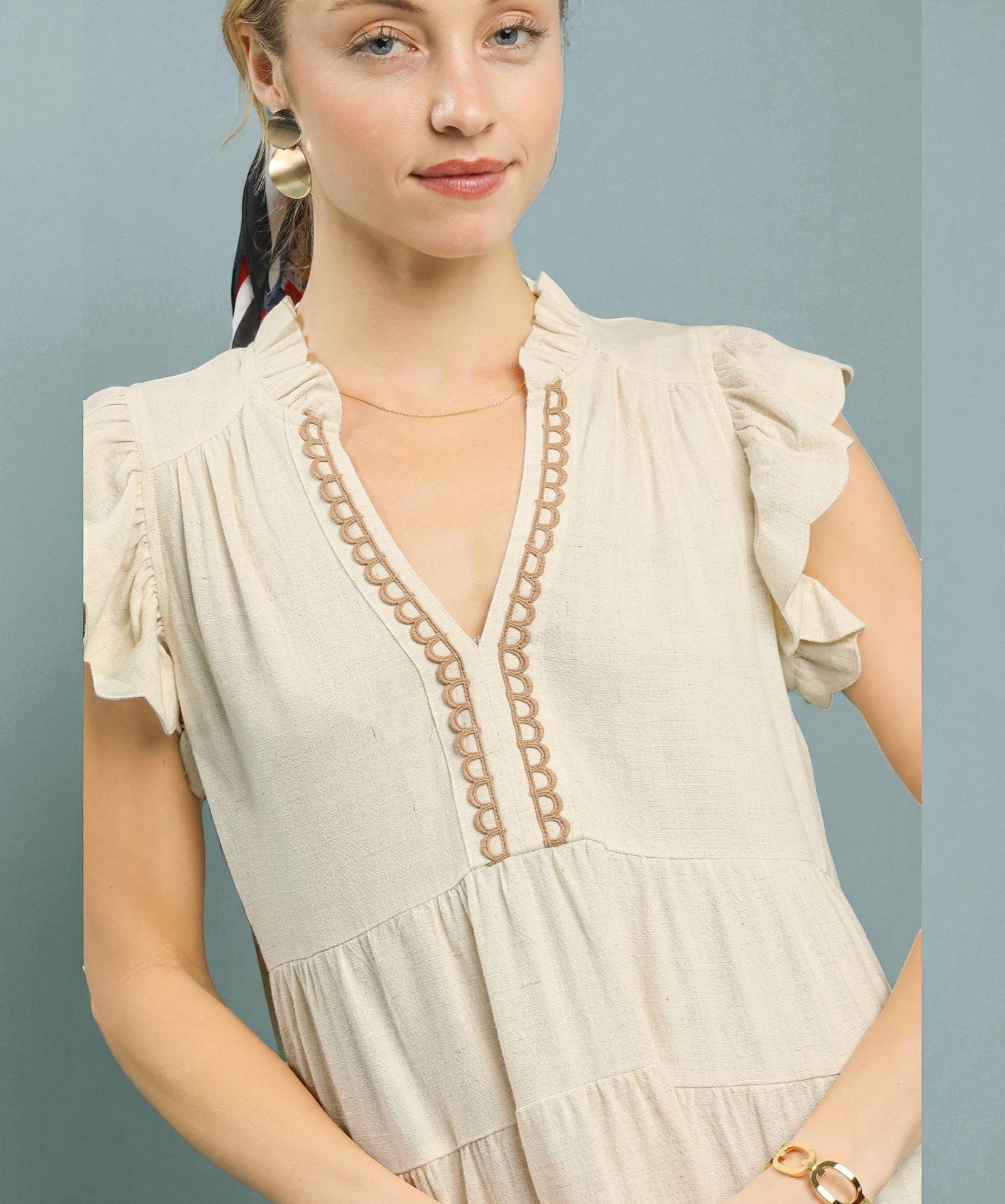 Woman wearing a beige dress with lace details on a gray background