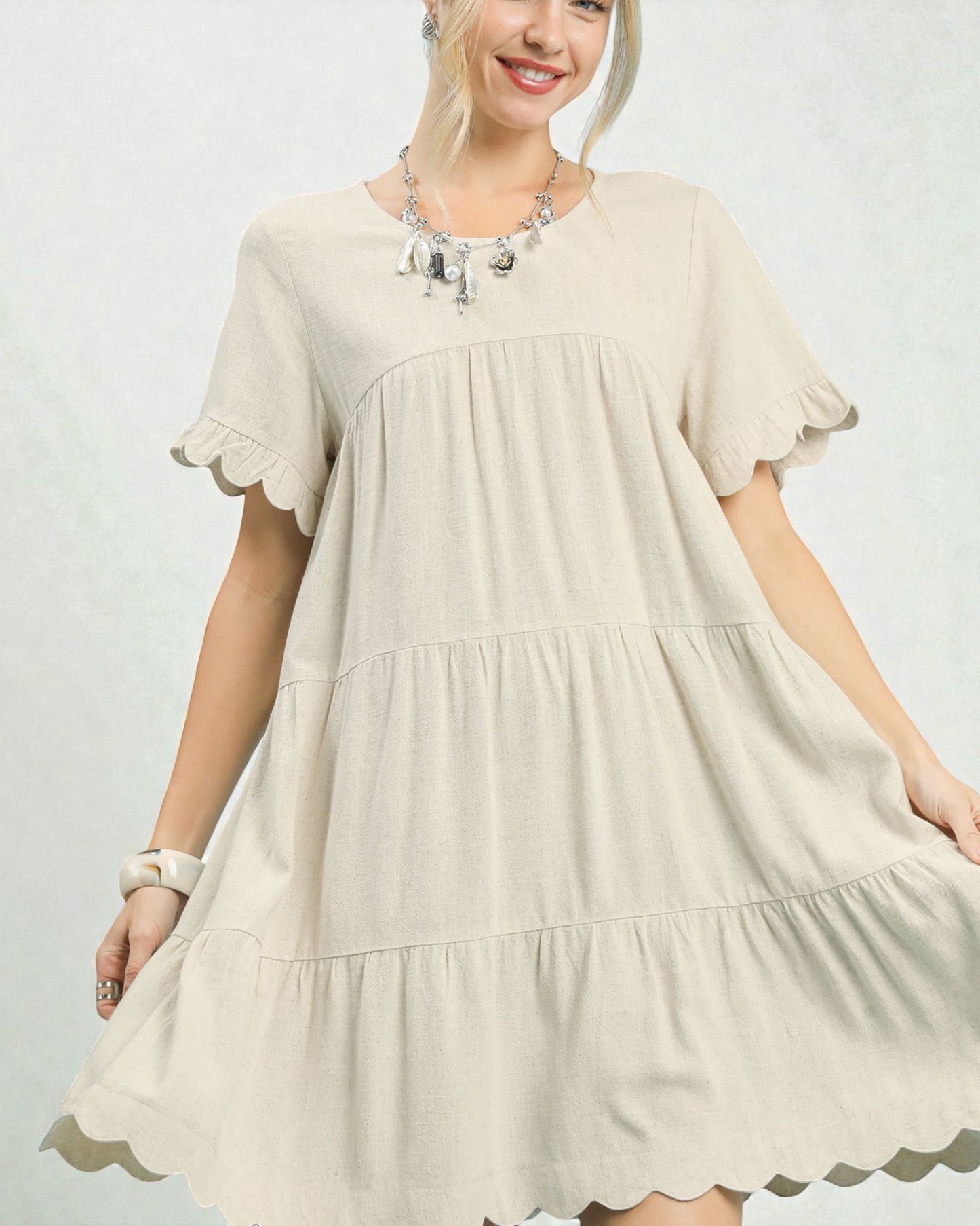 Woman wearing a beige dress with ruffled sleeves on a plain background