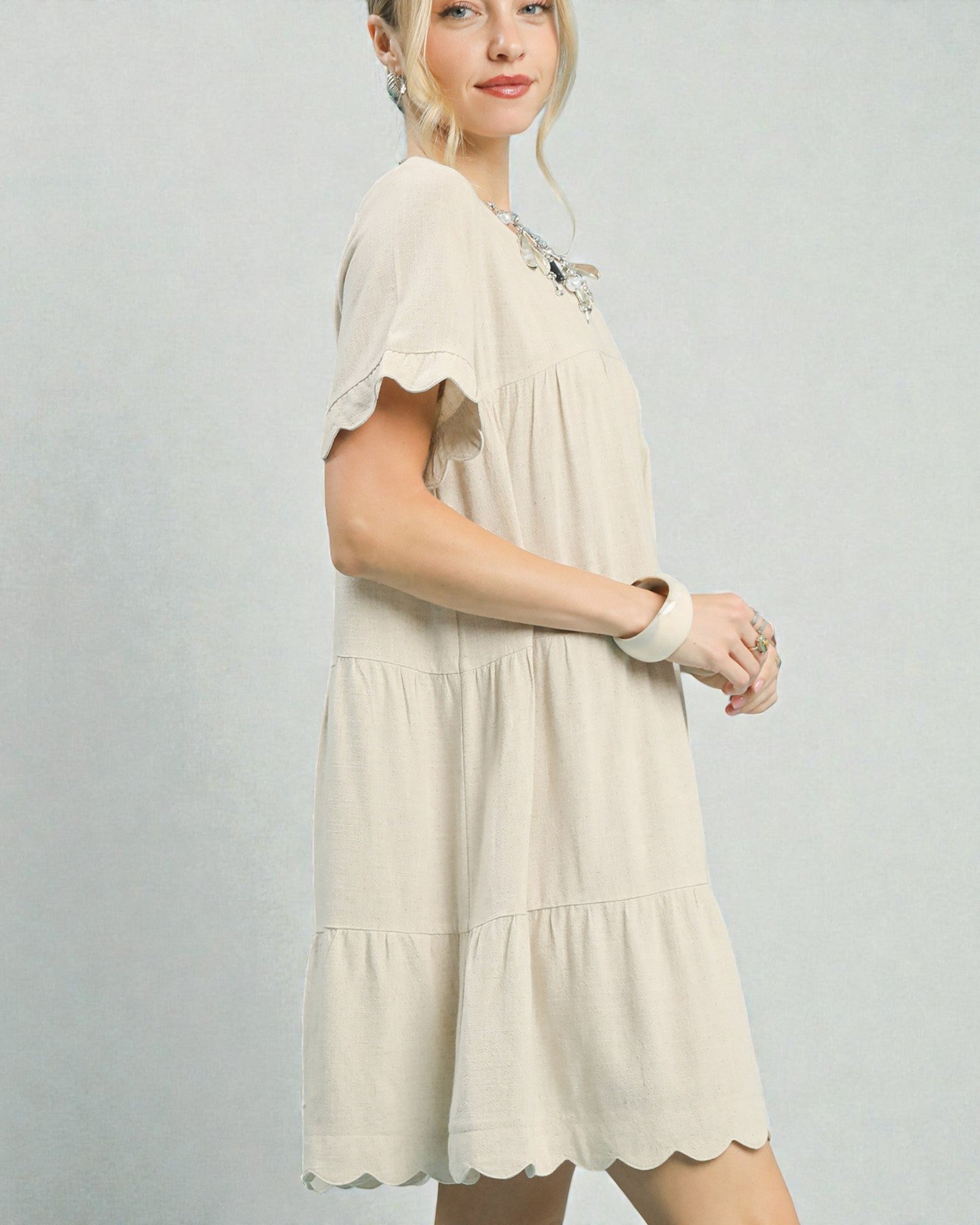 Woman wearing a beige dress against a plain background