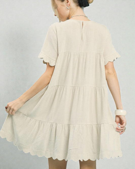 Beige dress worn by a person on a plain background