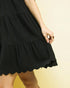 Black dress with scalloped hem on a yellow background