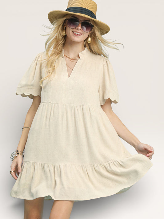 Woman wearing a beige dress and straw hat on a plain background