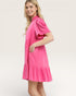 Woman wearing a pink dress with ruffled sleeves on a white background