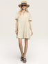 Woman wearing a beige dress and hat on a white background