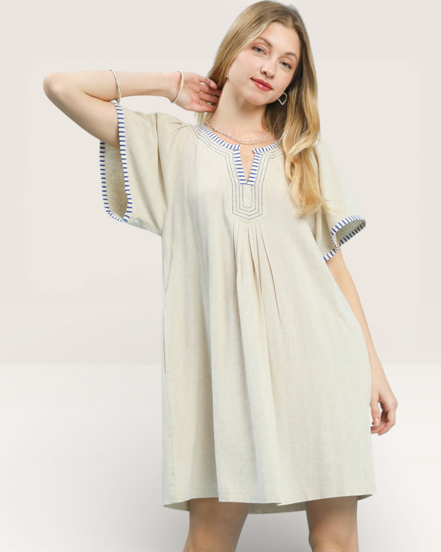 Woman wearing a beige dress with blue accents on a white background