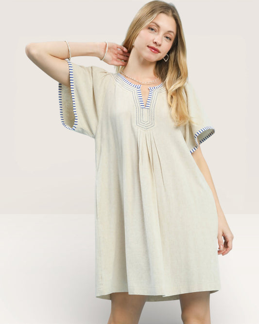 Woman wearing a beige dress with blue accents on a white background