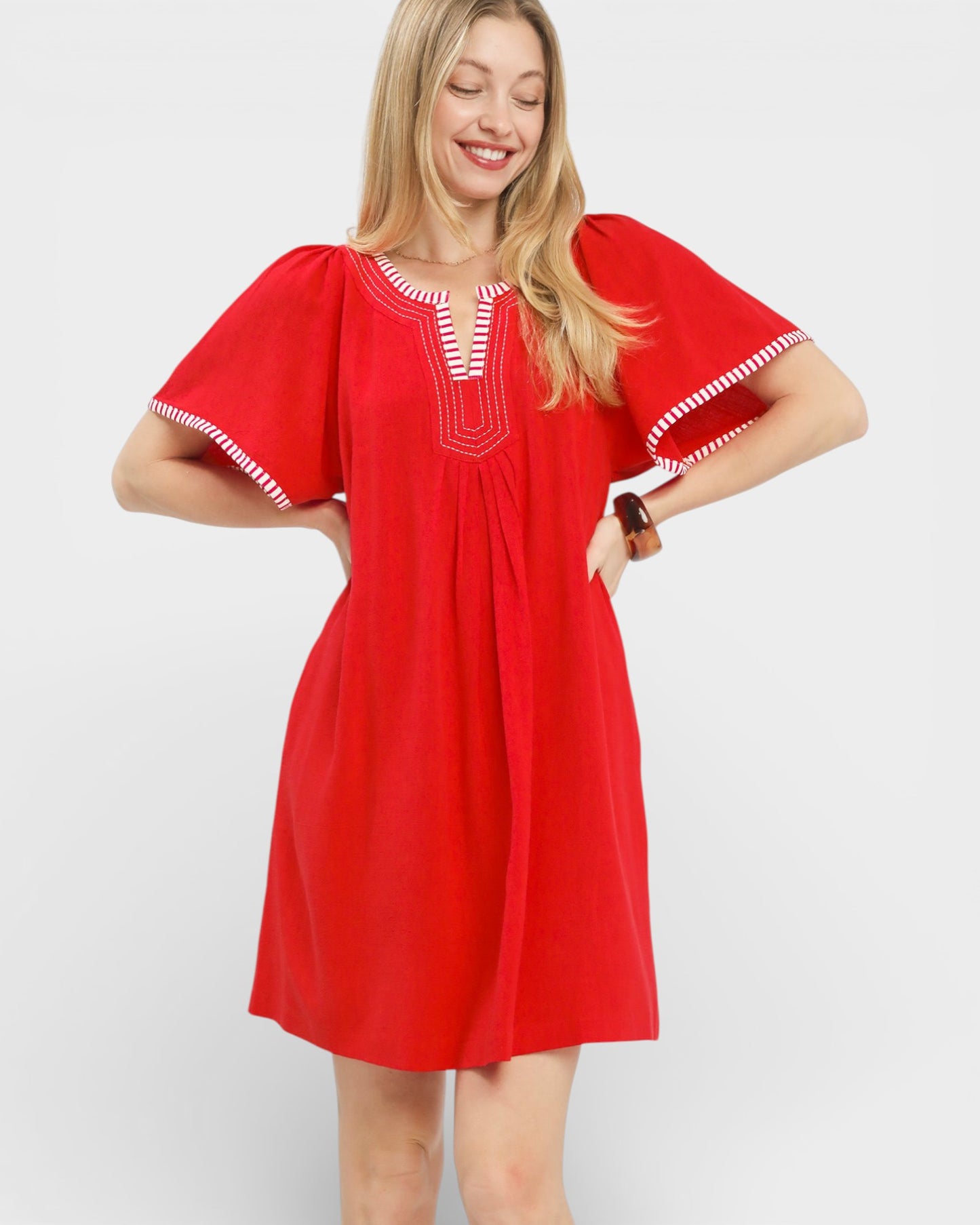 Woman wearing a red dress with white trim on a white background