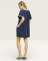 Woman wearing a navy dress with white trim on a plain background
