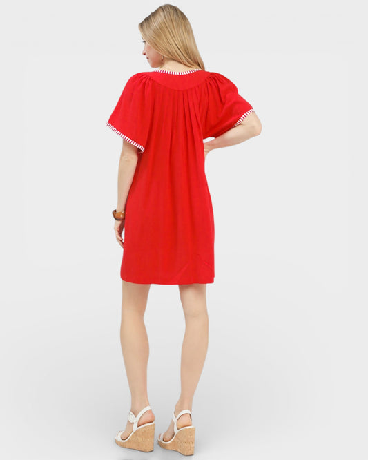 Woman wearing a red dress with white trim on a white background