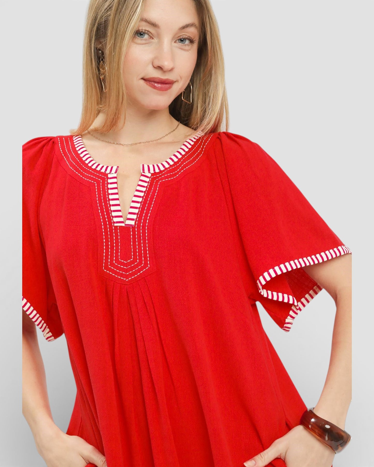 Woman wearing a red dress with white trim on a plain background