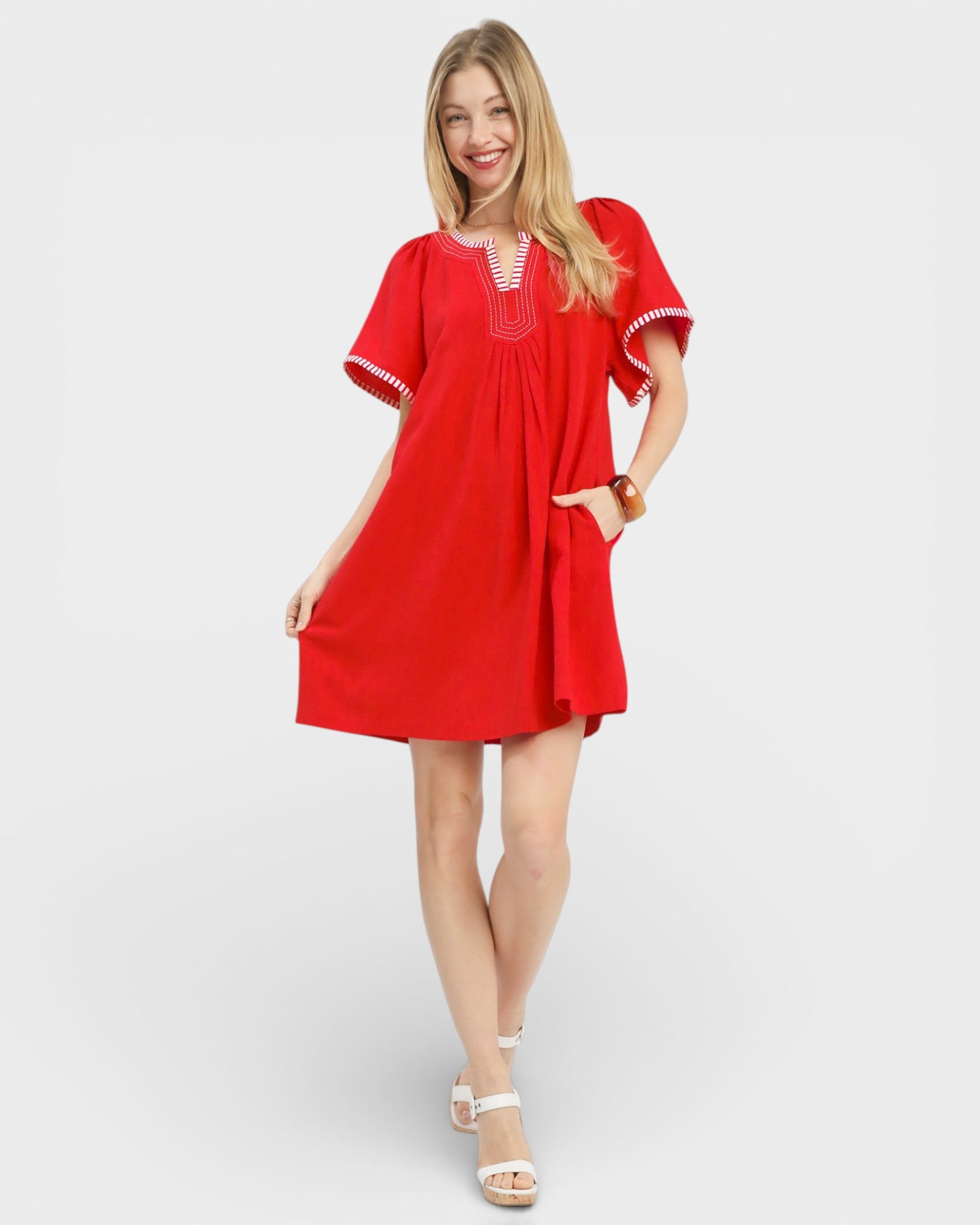 Woman wearing a red dress with white trim on a plain background