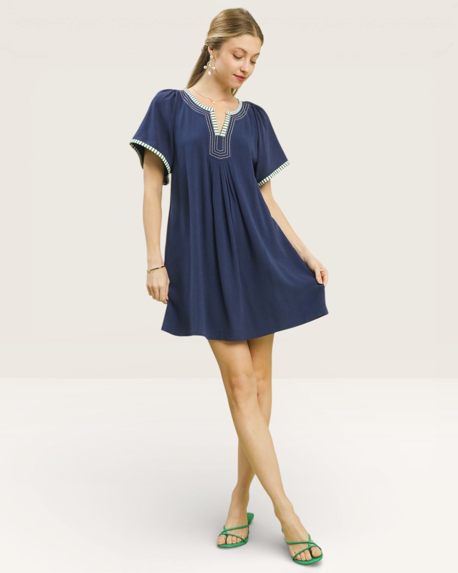 Woman wearing a blue dress with white trim on a plain background