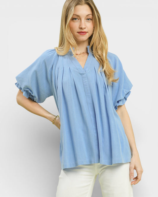Woman wearing a light blue blouse with ruffled sleeves on a white background
