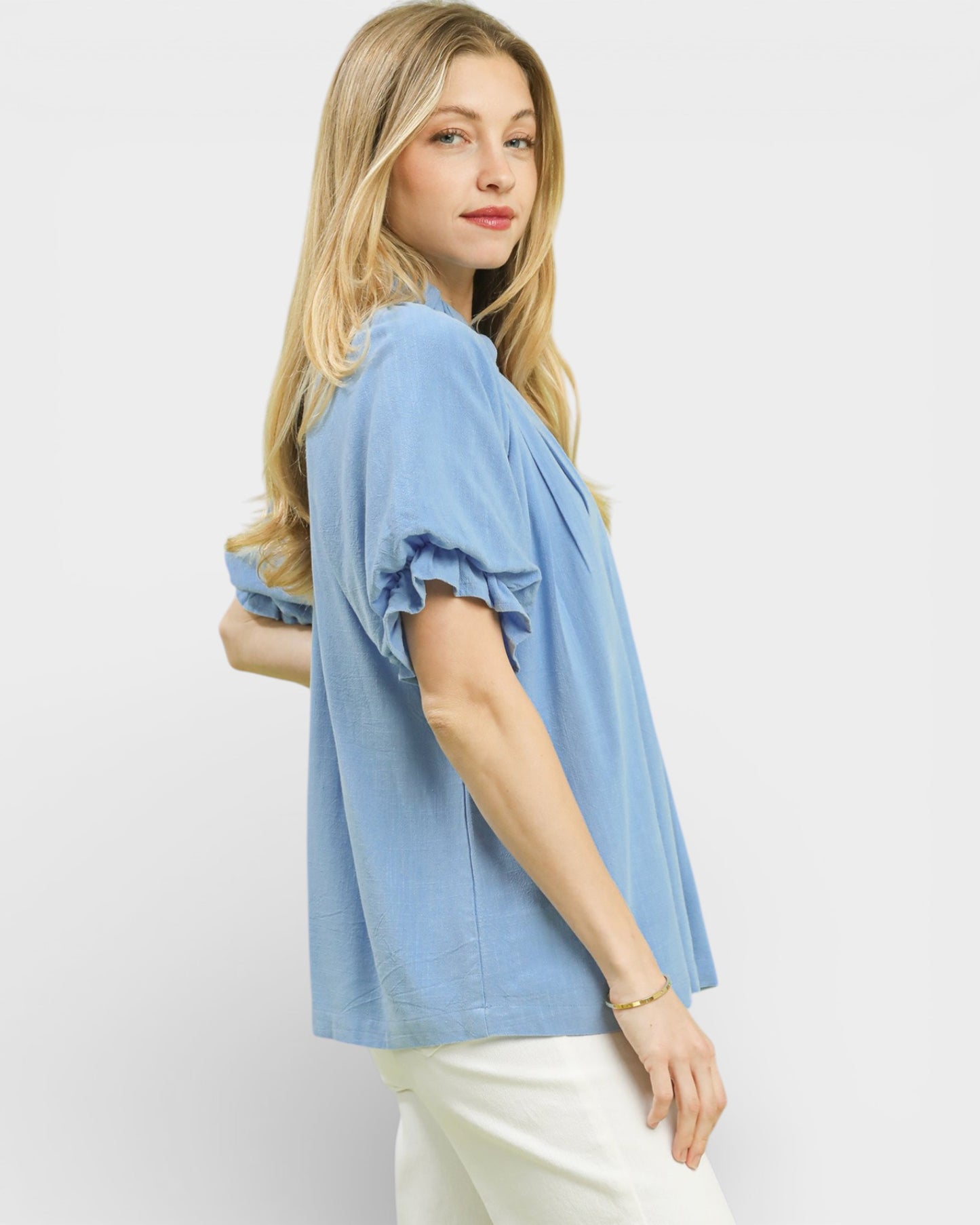 Woman wearing a light blue blouse with ruffled sleeves on a white background