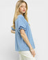 Woman wearing a light blue blouse with ruffled sleeves on a white background