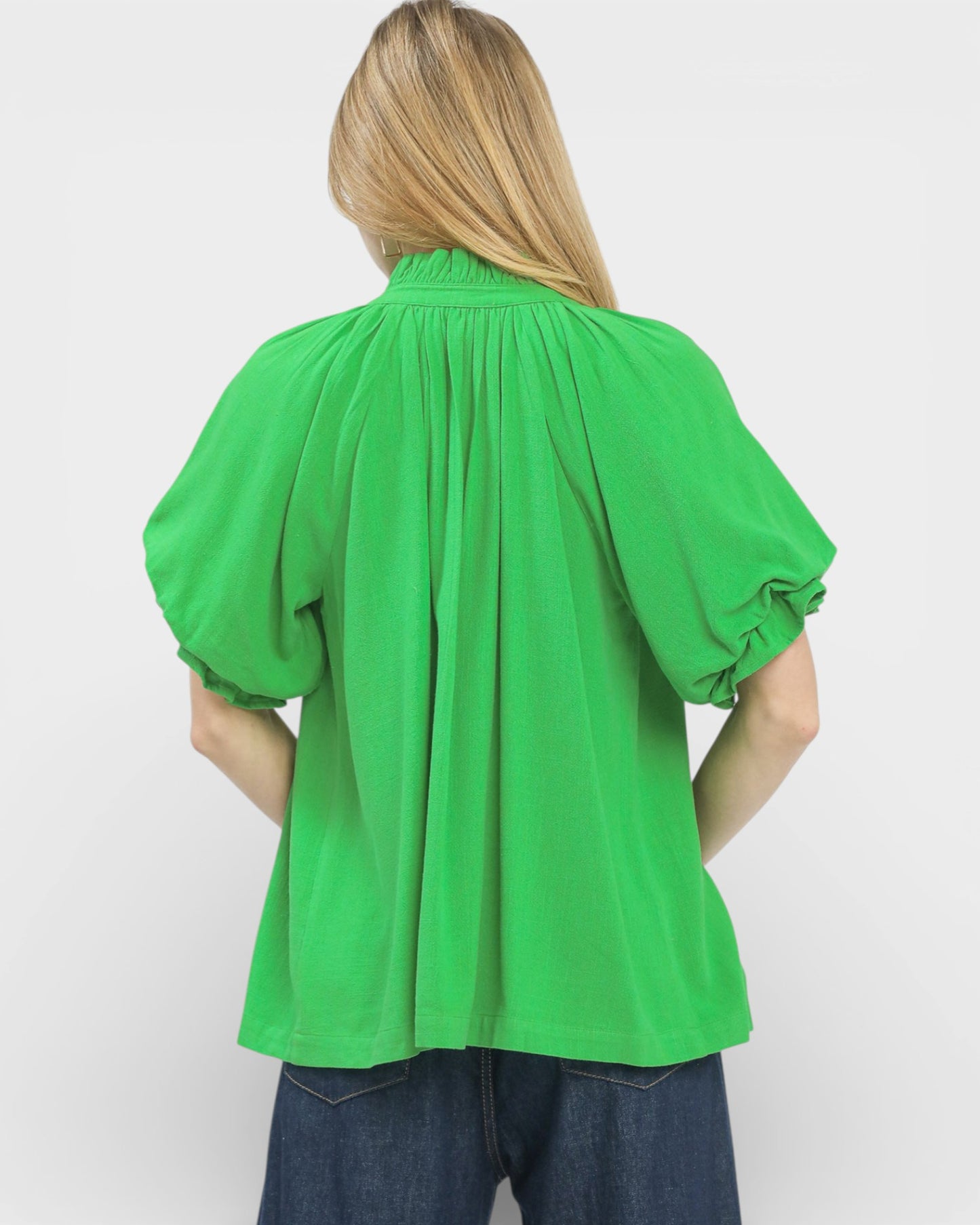 Person wearing a bright green blouse with puffed sleeves on a white background