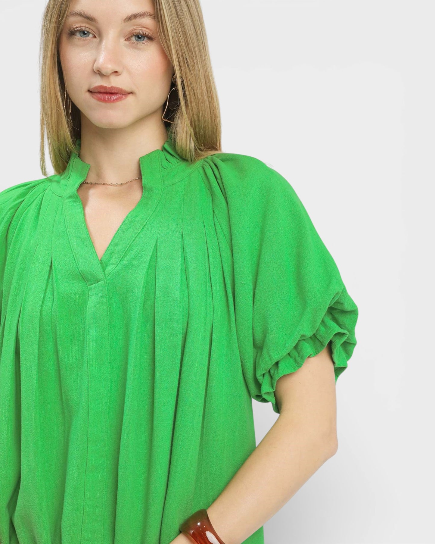 Woman wearing a green blouse with short sleeves on a white background