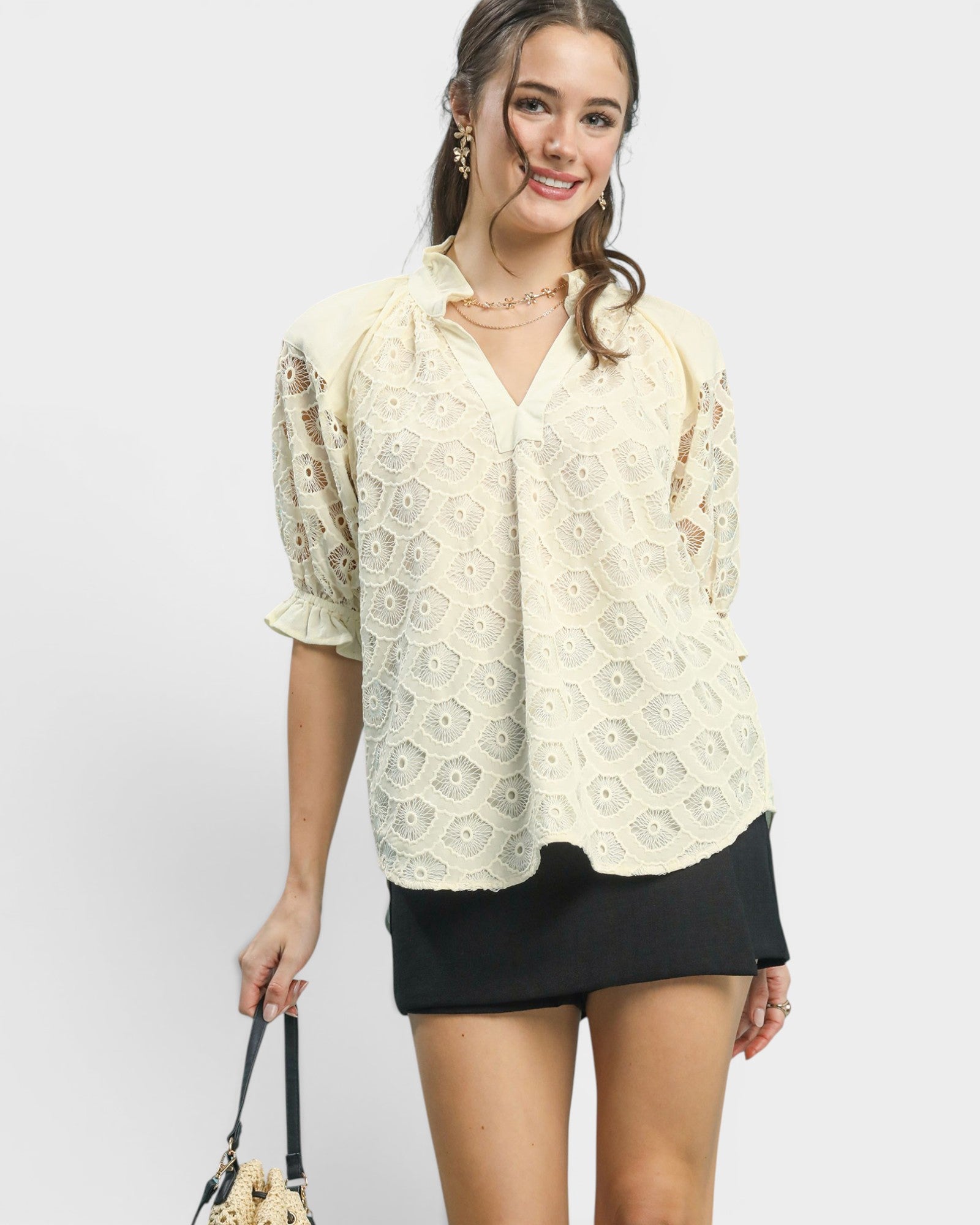 Woman wearing a cream lace blouse and black skirt on a white background