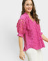 Woman wearing a pink lace blouse against a white background