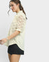 Woman wearing a cream lace top and black shorts on a plain background