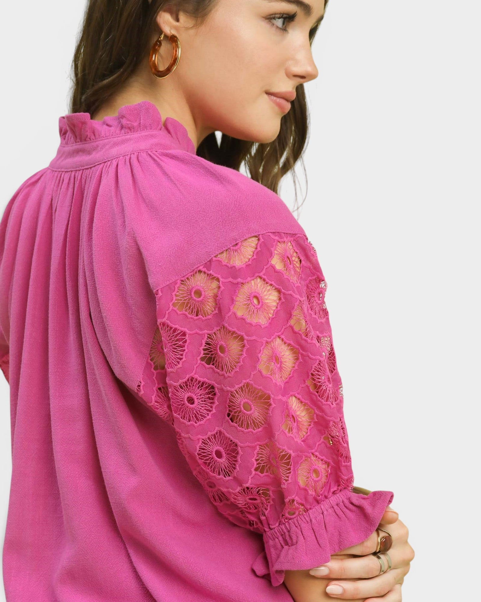 Close-up of a pink blouse with lace detailing on a plain background