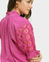 Close-up of a pink blouse with lace detailing on a plain background