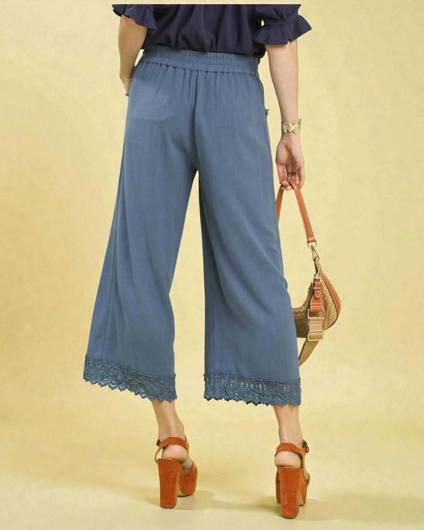 Person wearing blue lace-trimmed pants on a beige background