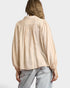 Person wearing a beige blouse with balloon sleeves on a plain background