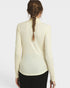 A woman viewed from the back wearing a fitted long-sleeve mock-neck top in a warm off-white/cream color, paired with black bottoms, against a light gray studio background.