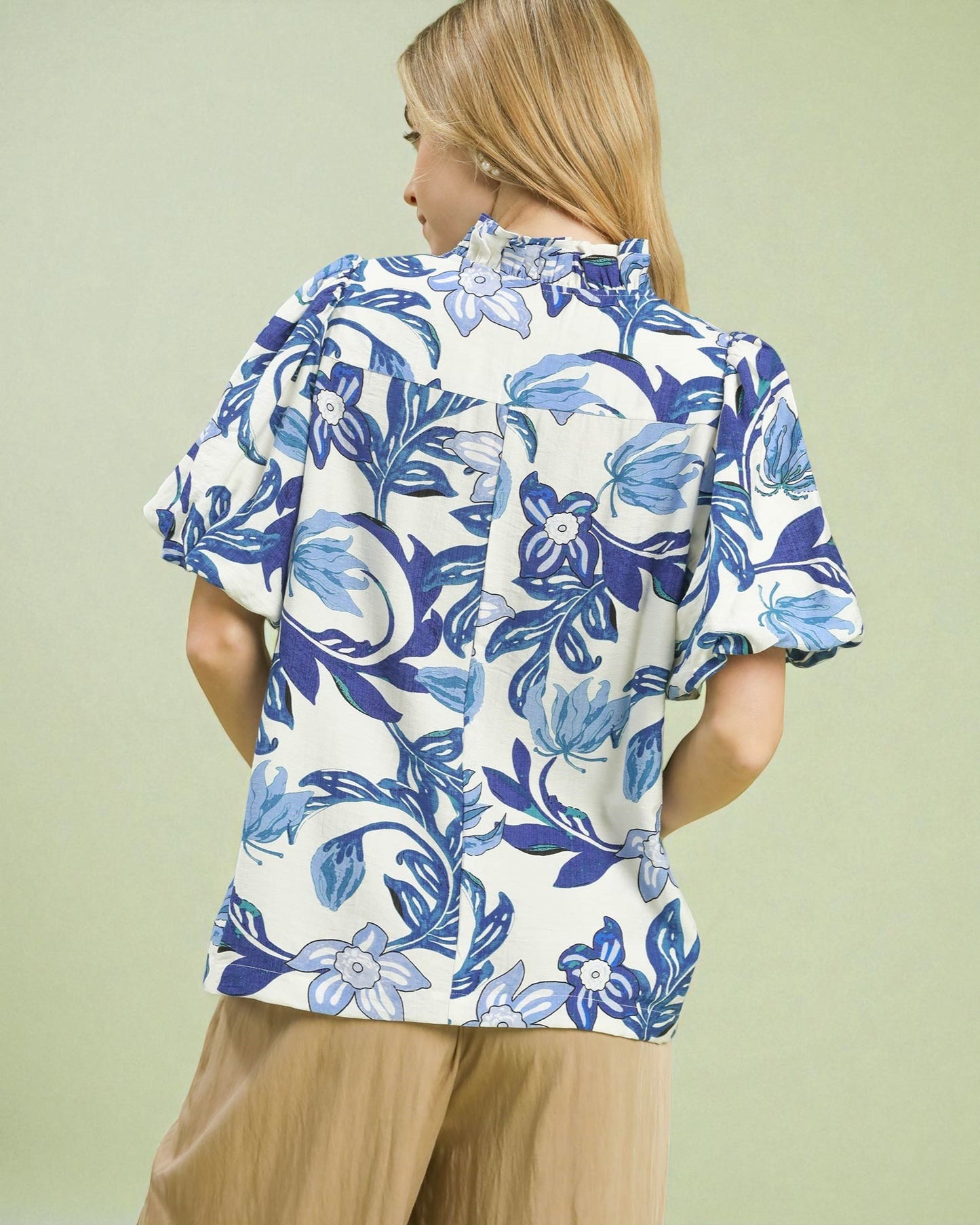 Woman wearing a blue and white floral blouse against a light green background