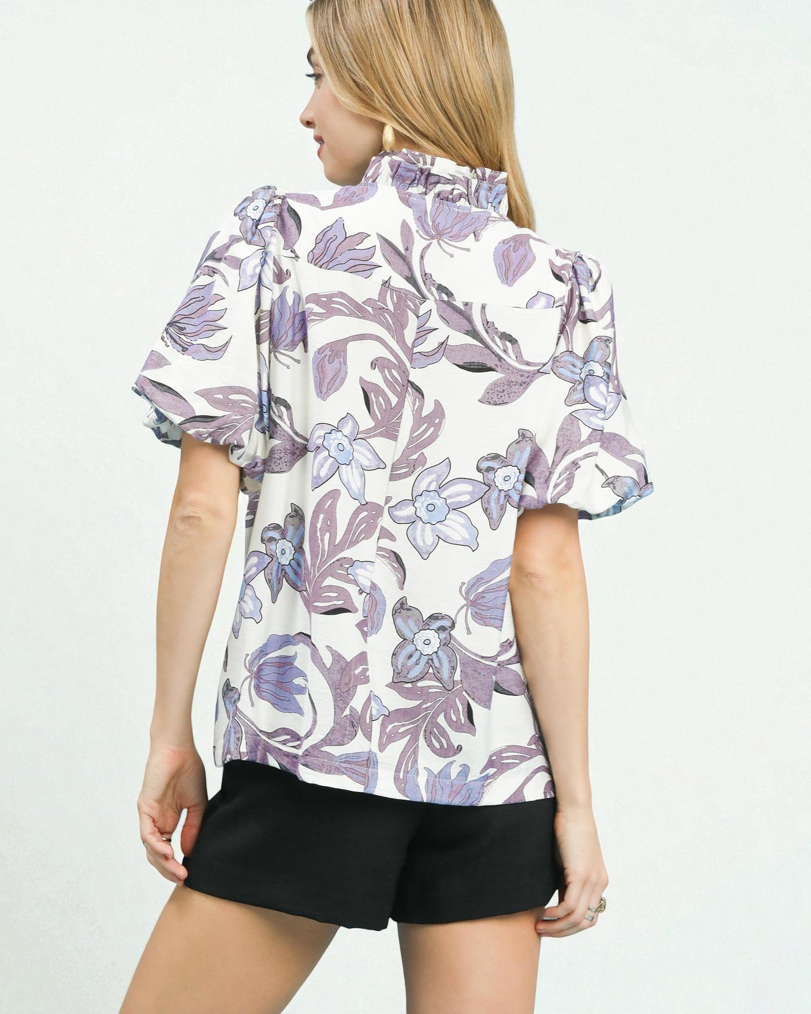 Woman wearing a floral blouse with puff sleeves on a white background