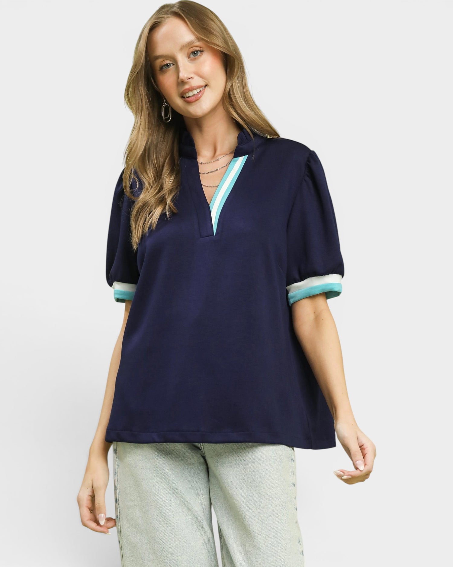 Woman wearing a navy blue polo shirt with light blue trim on a white background