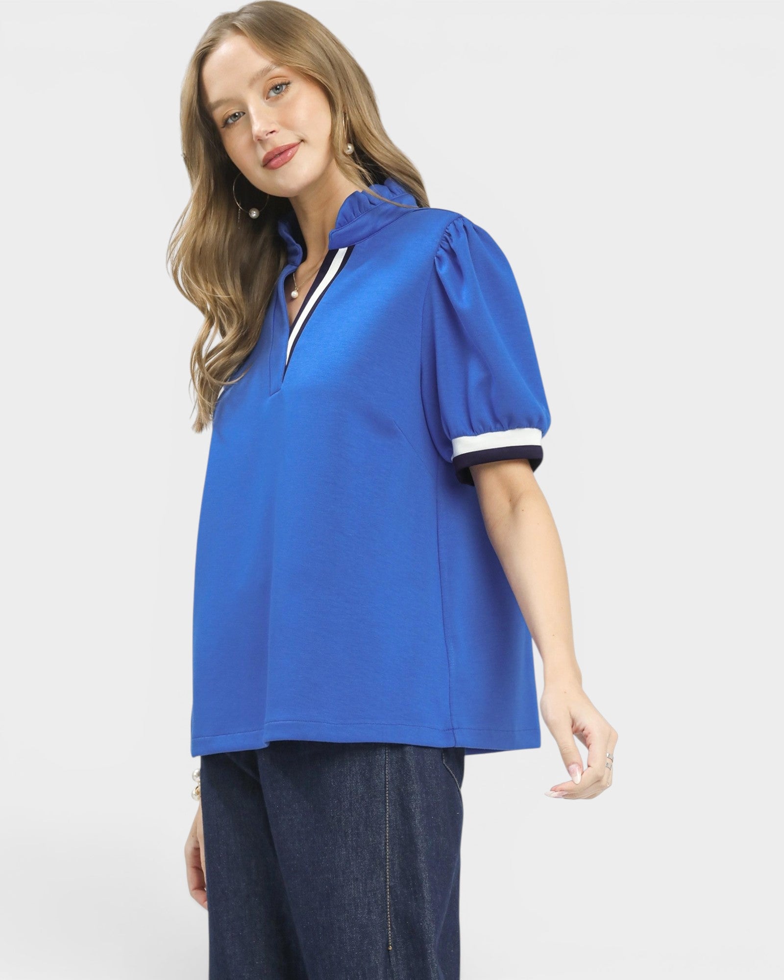 Woman wearing a blue blouse with white accents on a light gray background