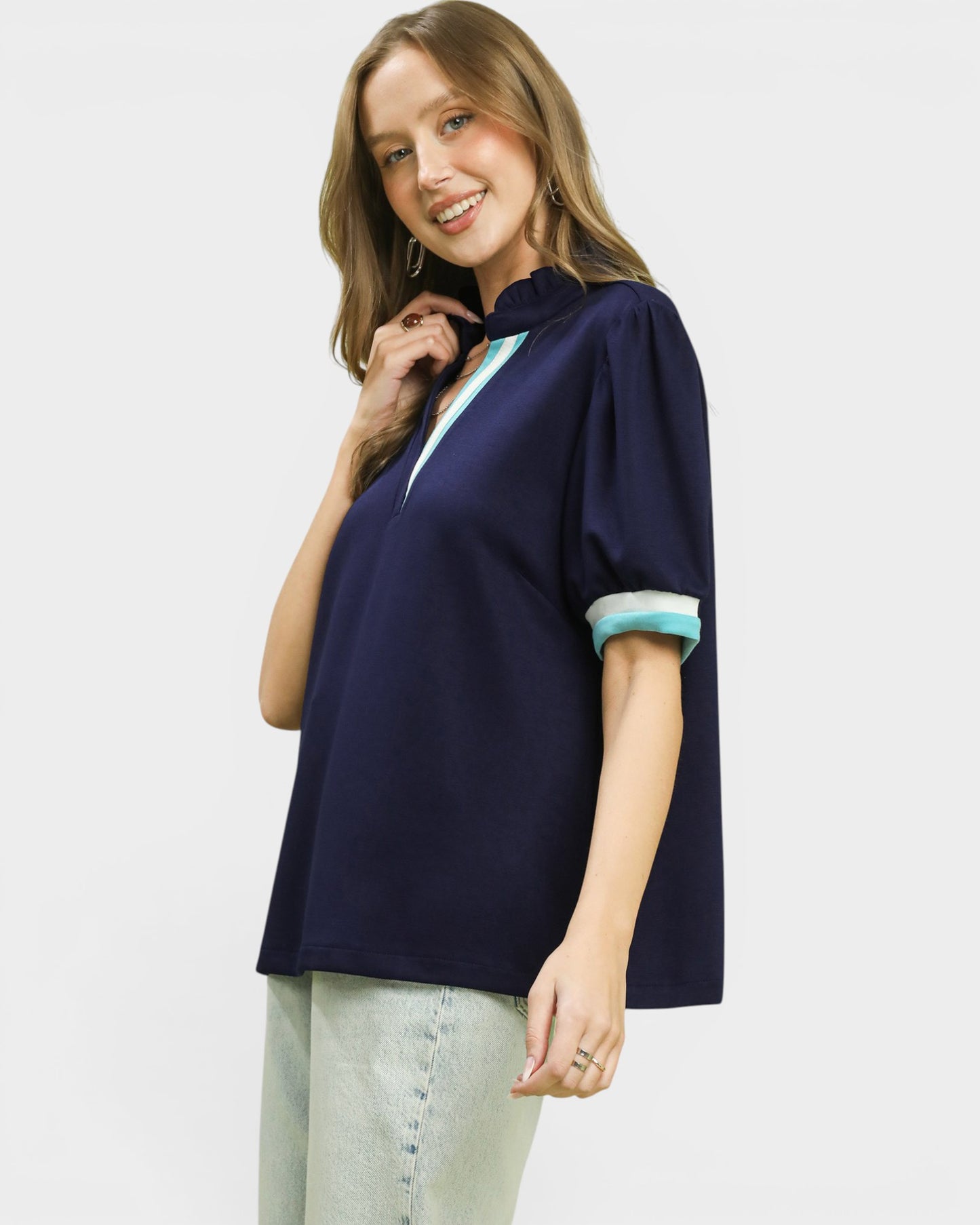 Woman wearing a navy blue blouse with light blue trim on a white background