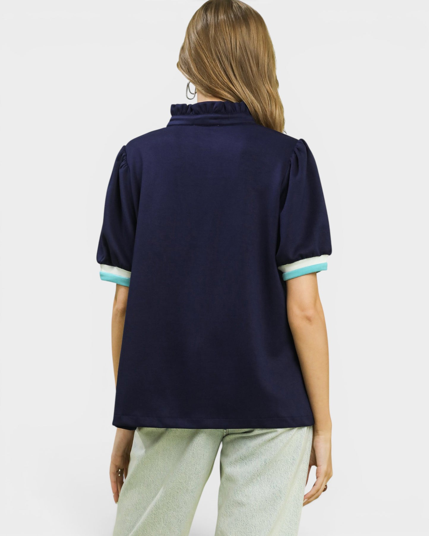 Woman wearing a navy blue polo shirt with light green trim on a white background