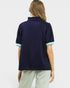 Woman wearing a navy blue polo shirt with light green trim on a white background