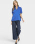 Woman wearing a blue top and dark jeans on a white background