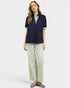 Woman wearing a navy blue top with green trim and light green pants on a white background