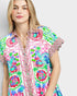 Woman wearing a colorful patterned shirt on a plain background