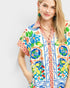 Woman wearing a colorful floral and patterned shirt on a white background