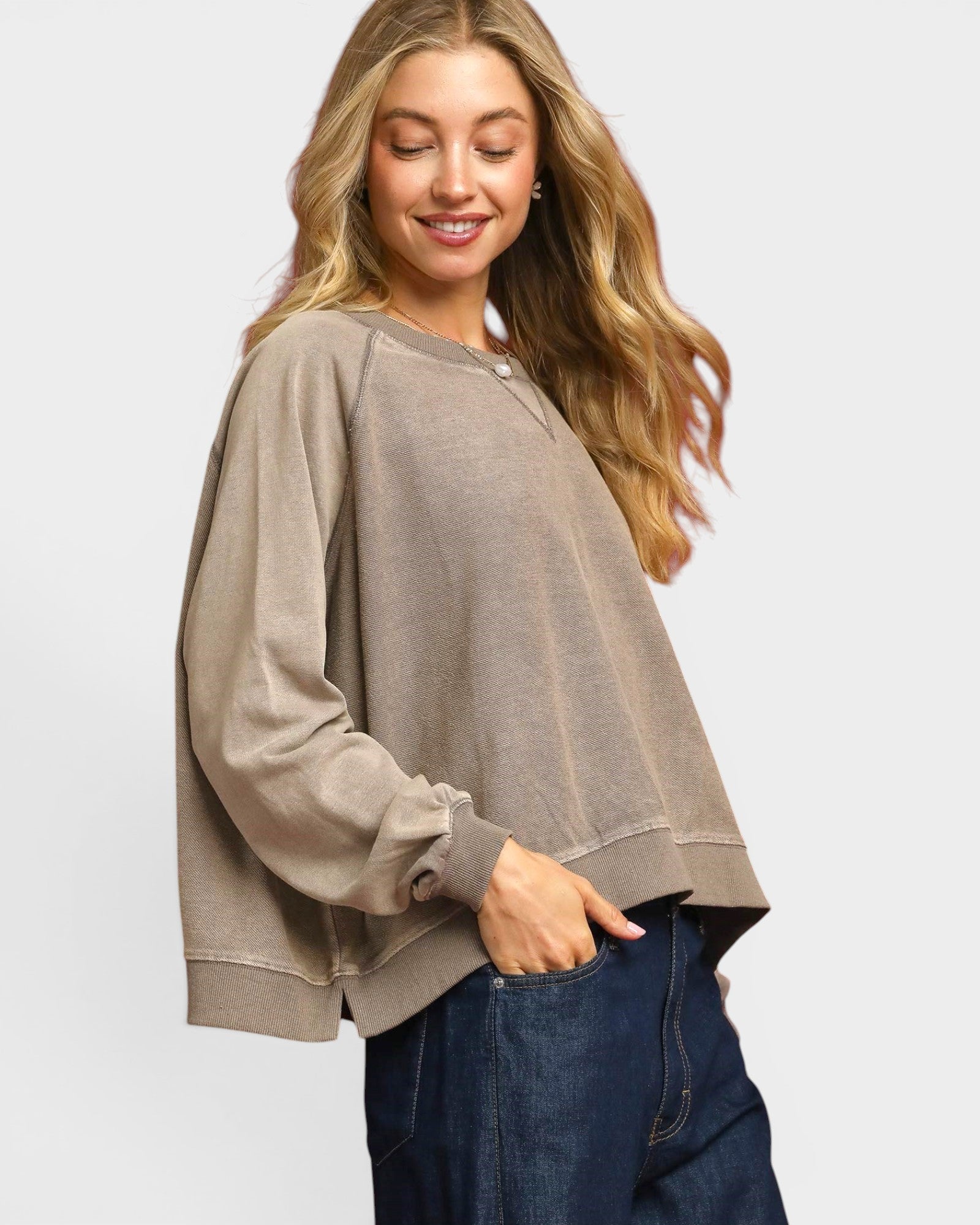 Woman wearing a beige sweater and blue jeans on a white background