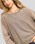 Woman wearing a beige sweater against a plain background