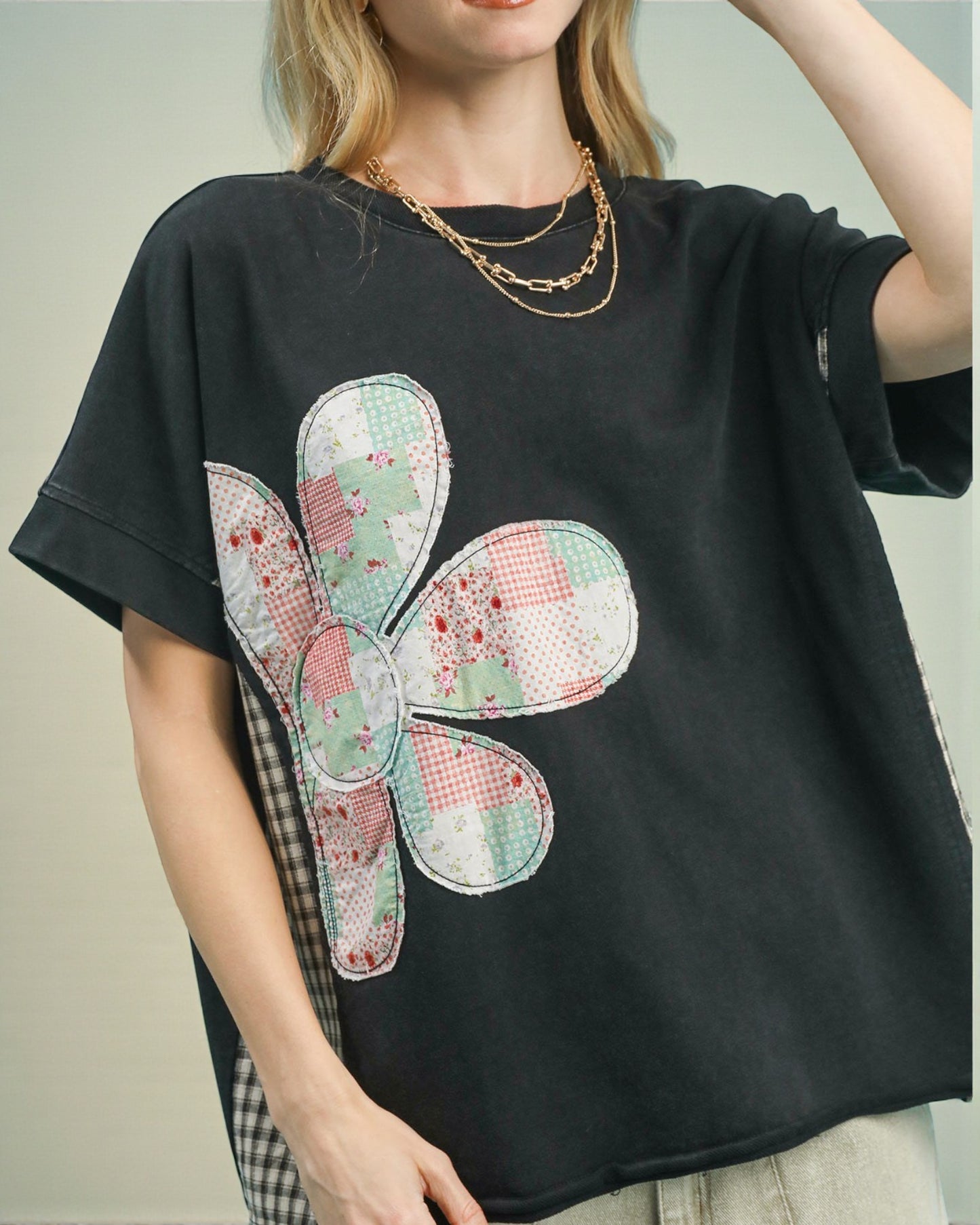 Black t-shirt with a colorful flower patch worn by a person