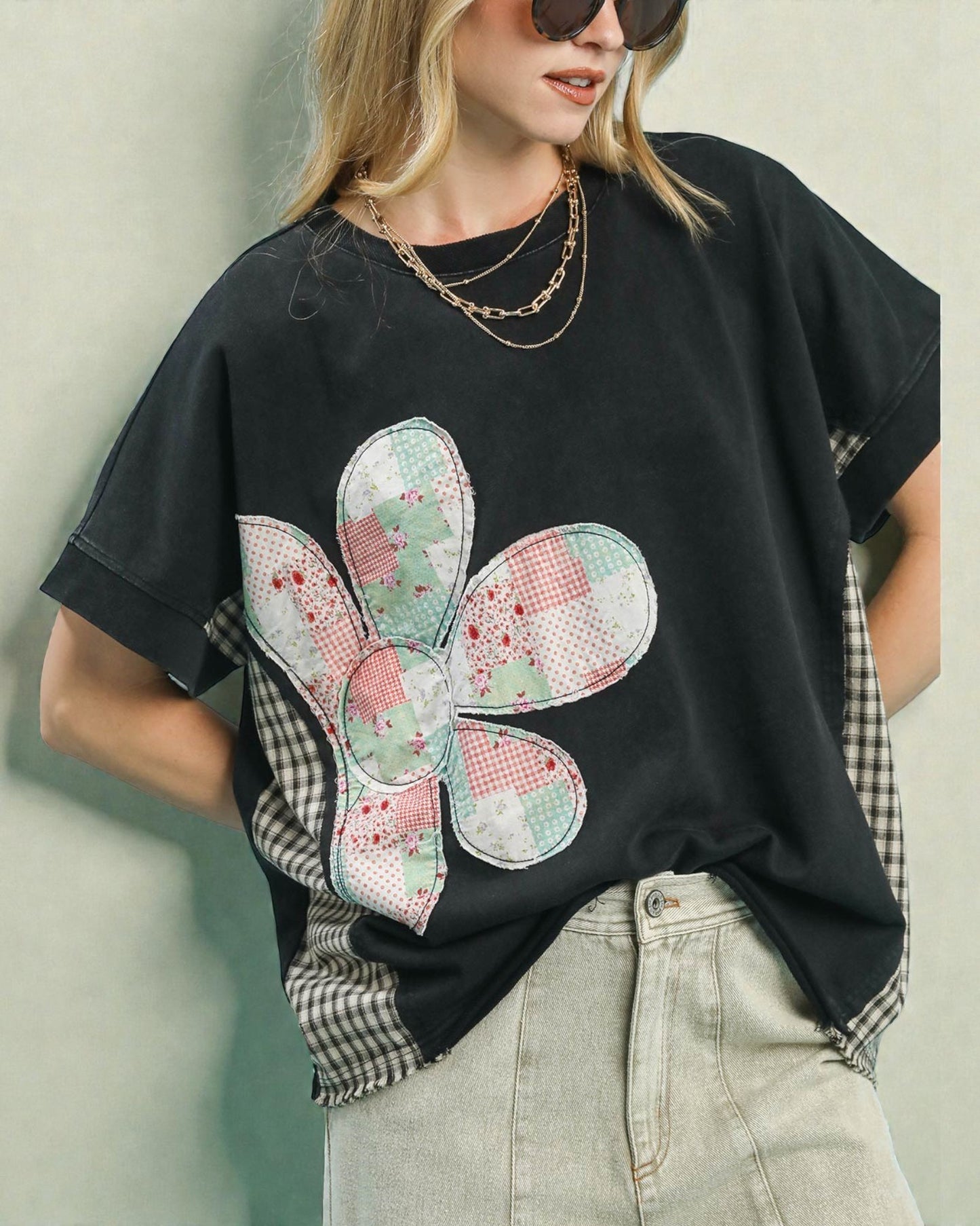 Person wearing a black t-shirt with a colorful butterfly patch on a plain background